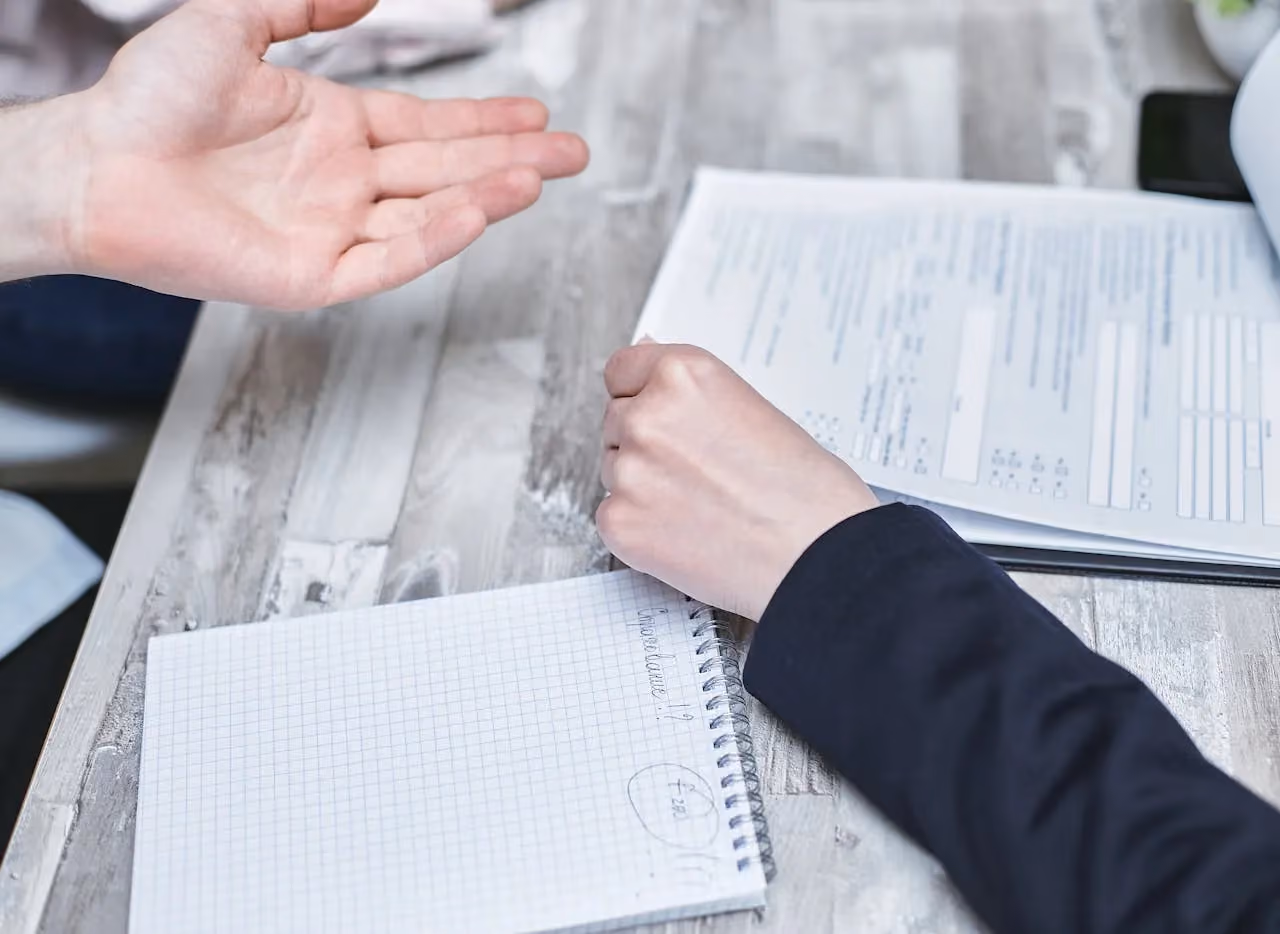 Documents spread across a table during a business discussion, representing the volume of paperwork that AI can automate