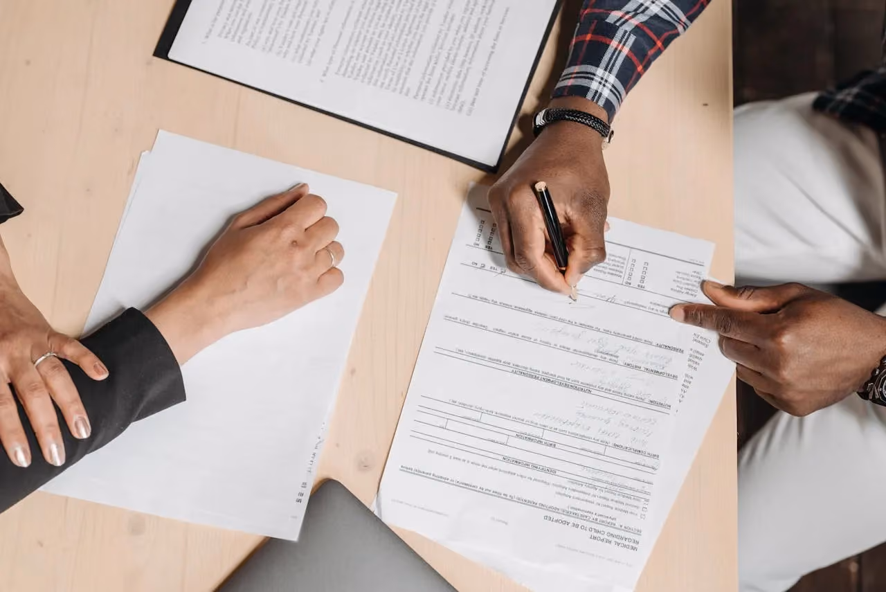 Two people reviewing paperwork and documents at an office desk