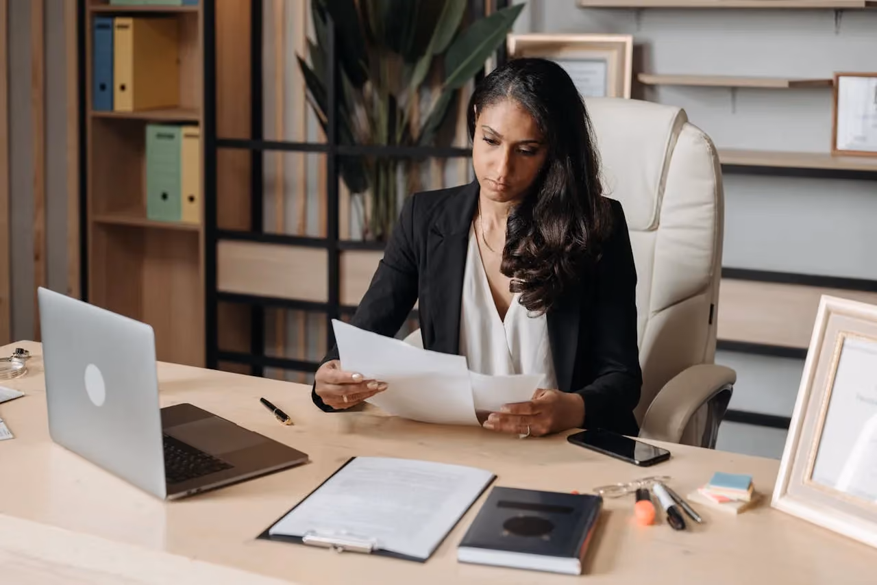 Woman focused on administrative work at an office desk surrounded by documents