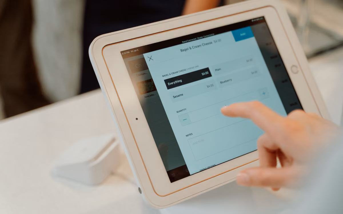 Person tapping an order screen on a tablet mounted at a shop counter