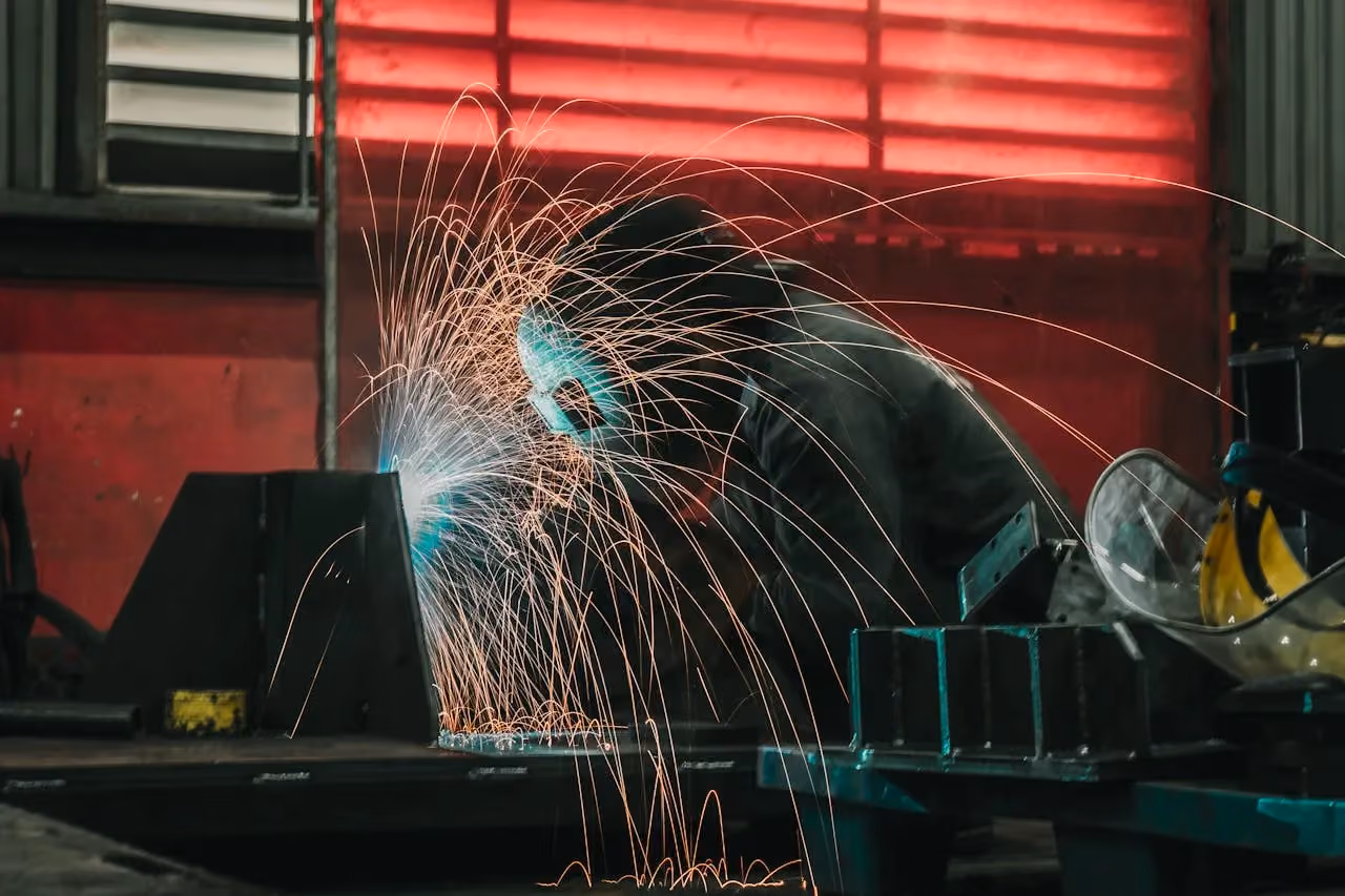 Welder creating sparks while fabricating metal in an industrial workshop