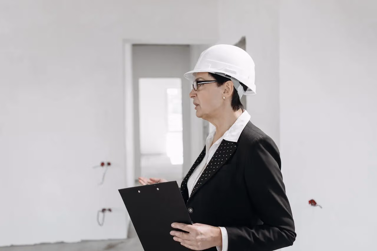 Professional inspector with hard hat and clipboard reviewing a site