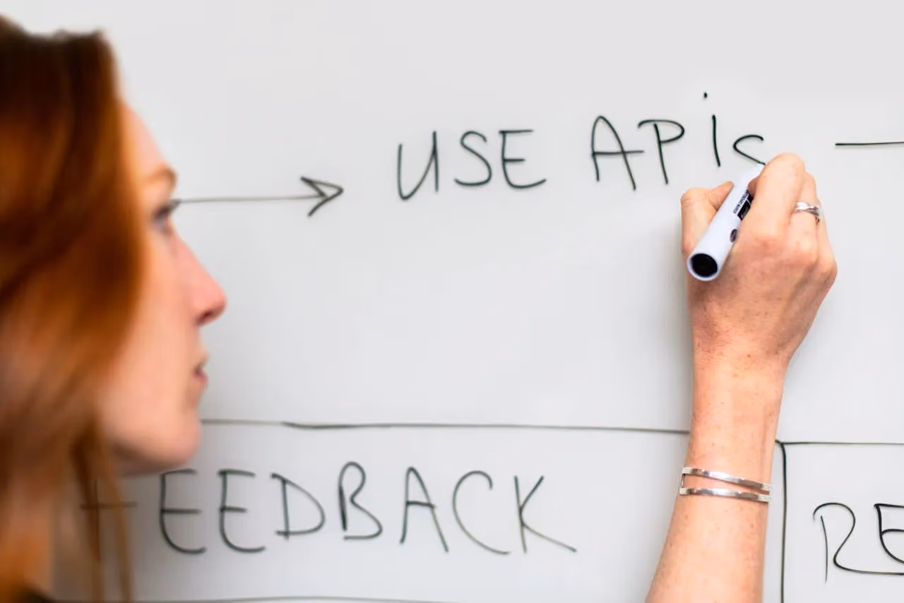 Woman writing project goals and ideas on a whiteboard during a planning session