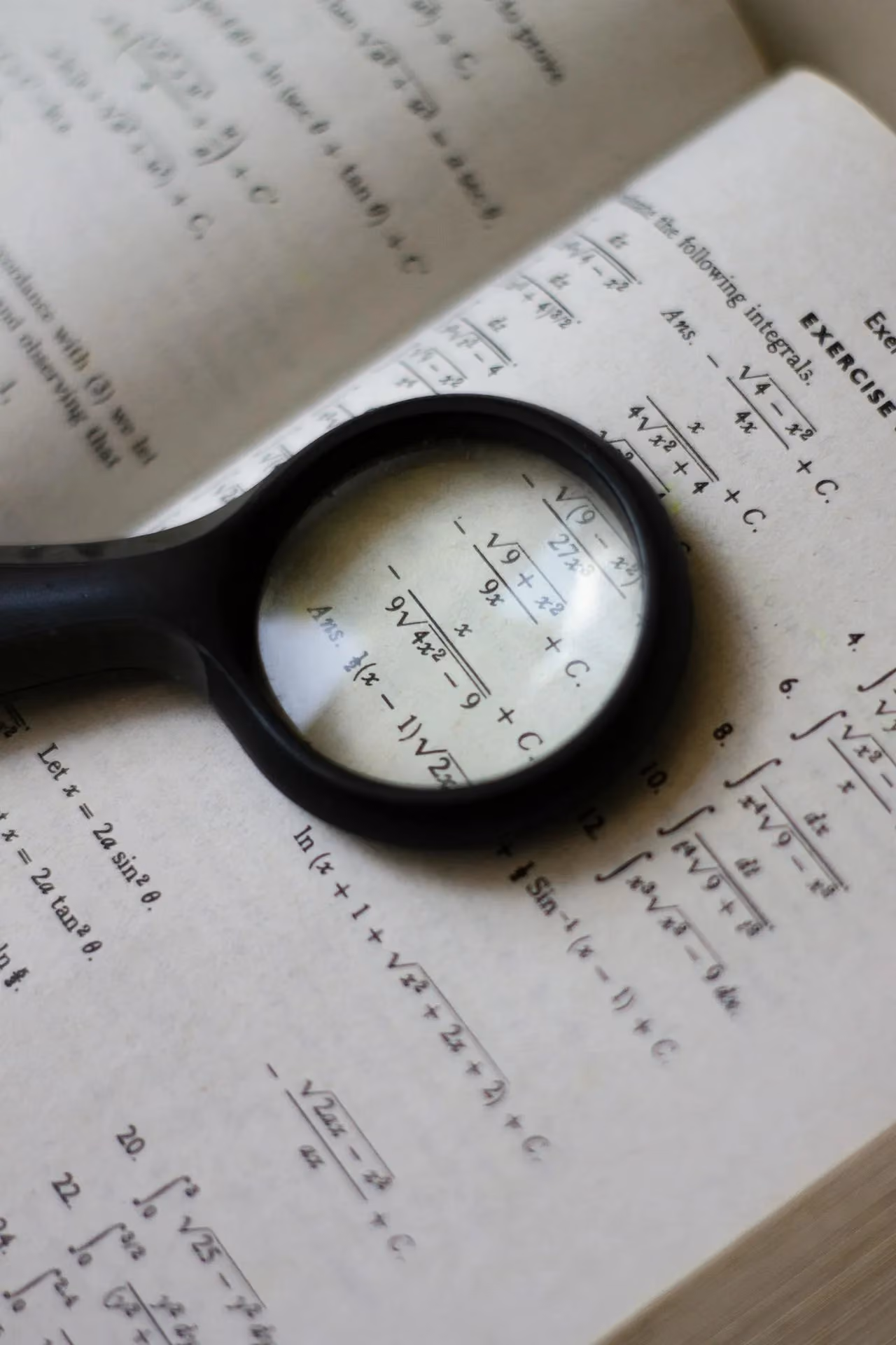 Magnifying glass resting on an open textbook, emphasising research and detailed reading