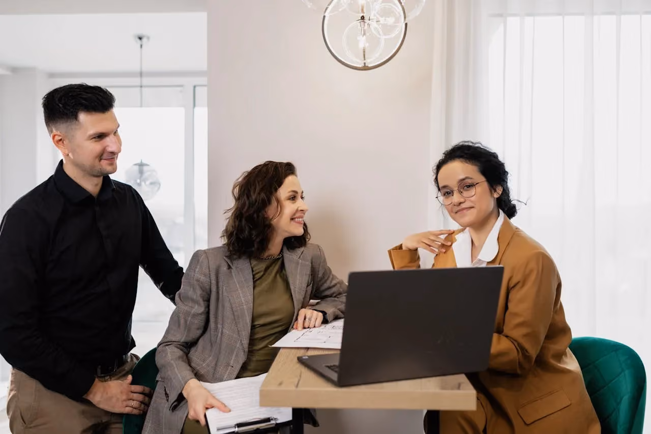 Consultant presenting information on a laptop to two business owners at a desk