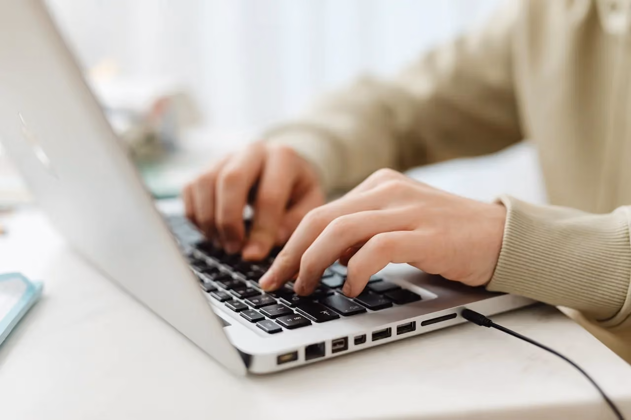 A person typing on a laptop, creating website content that AI search tools can reference and cite