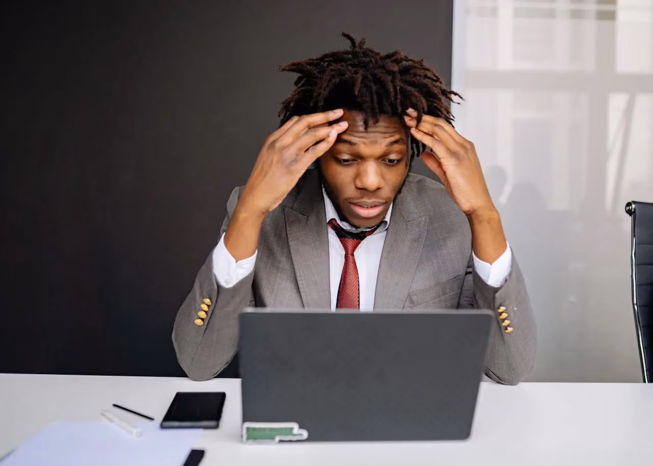 Frustrated business owner staring at laptop screen with hands on head