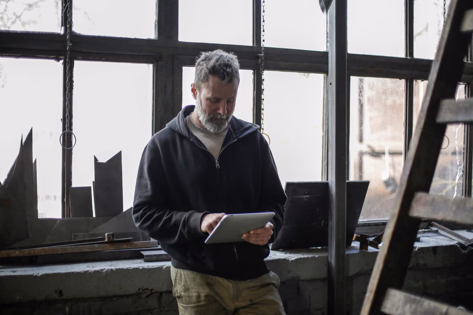 A workshop floor with an engineer reviewing production information on a tablet